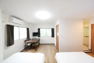 a bedroom with two beds and a desk and a table at \u548c\u306e\u6953cottage\u7b2c\u4e8c302 \u65b0\u5bbf\u6b4c\u821e\u4f0e\u753a\u8fd1\u96a3 in Tokyo