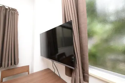 a flat screen tv on a wall next to a window at \u548c\u306e\u6953cottage\u7b2c\u4e8c302 \u65b0\u5bbf\u6b4c\u821e\u4f0e\u753a\u8fd1\u96a3 in Tokyo