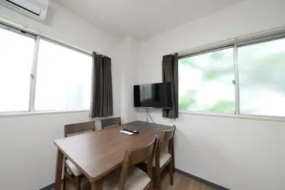 a room with a table with chairs and a tv at \u548c\u306e\u6953cottage\u7b2c\u4e8c302 \u65b0\u5bbf\u6b4c\u821e\u4f0e\u753a\u8fd1\u96a3 in Tokyo