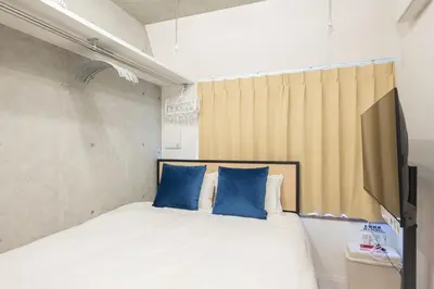 a bedroom with a bed with two blue pillows at Ferio\u84b2\u7530III in Tokyo