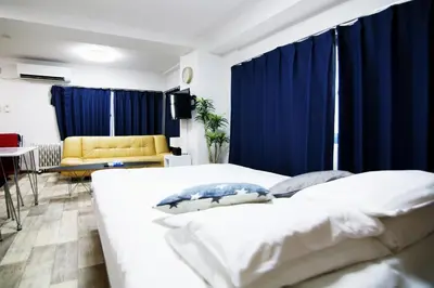 a bedroom with blue curtains and a bed and a couch at \u5927\u68ee\u30db\u30c6\u30eb \u30d3\u30c3\u30b0\u30d5\u30a9\u30ec\u30b9\u30c8 in Tokyo