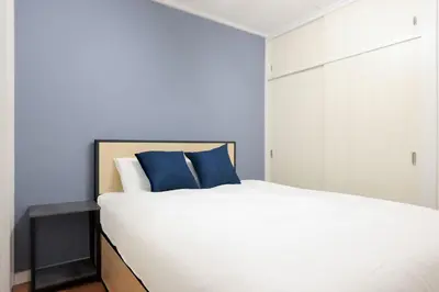 a bedroom with a large white bed with blue pillows at \u65b0\u5bbf\u5ca1\u7530\u30d3\u30eb in Tokyo