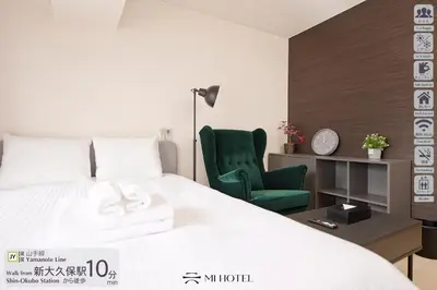a bedroom with a bed and a green chair at Shinjuku Kabukicho Harmony Inn in Tokyo