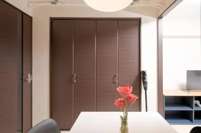 a vase of flowers on a table in front of a closet at Shinjuku Kabukicho Harmony Inn in Tokyo