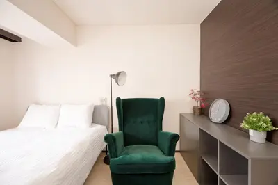 a bedroom with a bed and a green chair at Shinjuku Kabukicho Harmony Inn in Tokyo