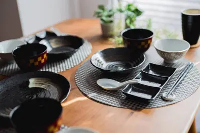 a wooden table with black plates and bowls and spoons at Akihabara Area! Direct to Shibuya, Narita, Haneda in Tokyo