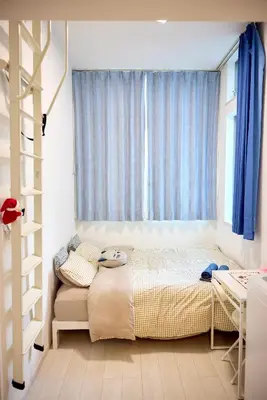 a bedroom with a bed and a window with blue curtains at \u5bbf\u6816\u6e0b\u8c37 in Tokyo