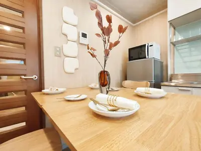 a wooden table with plates and flowers in a kitchen at 65 \u4e24\u5ba4\u4e00\u5385 \u99d2\u8fbc\u7ad94\u5206 \u8fd1\u5546\u4e1a\u8857 2 rooms 4 mins to ST Max 7P \u76f4\u8fbe\u65b0\u5bbf \u6d89\u8c37 \u8868\u53c2\u9053 \u6c60\u888b \u4e0a\u91ce \u4ee3\u4ee3\u6728 \u94f6\u5ea7 \u539f\u5bbf in Tokyo