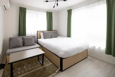 a bedroom with a bed and a window with green curtains at aLATO\u5927\u68ee\u753a in Tokyo