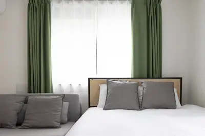 a bedroom with a bed with green curtains and a window at aLATO\u5927\u68ee\u753a in Tokyo