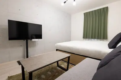a small room with two beds and a flat screen tv at aLATO\u5927\u68ee\u753a in Tokyo