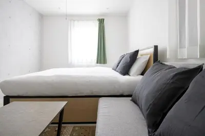 a bedroom with a bed and a couch and a window at aLATO\u5927\u68ee\u753a in Tokyo