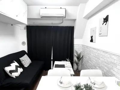 a living room with a black couch and white tables at Ikebukuro Sugamo \u99c5\u8fd1 C02 in Tokyo