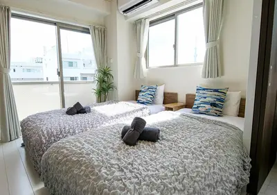 two beds in a room with windows at Asakusabashi Condominium Hotel in Tokyo