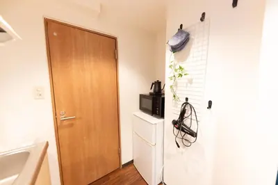 a bathroom with a wooden door and a refrigerator at TRIP PERCH 30m2 \u6700\u59275\u540d \u4e0a\u5317\u6ca2\u99c5\u304b\u3089\u5f92\u6b696\u5206 \u65b0\u5bbf\u304b\u3089\u76f4\u901a \u30c7\u30b6\u30a4\u30ca\u30fc\u76e3\u4fee in Tokyo