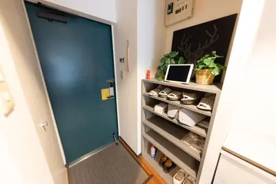 a hallway with a blue door and a shelf with shoes at TRIP PERCH 30m2 \u6700\u59275\u540d \u4e0a\u5317\u6ca2\u99c5\u304b\u3089\u5f92\u6b696\u5206 \u65b0\u5bbf\u304b\u3089\u76f4\u901a \u30c7\u30b6\u30a4\u30ca\u30fc\u76e3\u4fee in Tokyo