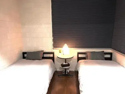 a room with two beds and a table with a window at Shibuya Harajuku Big House in Tokyo