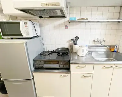 a kitchen with a microwave and a stove and a sink at 東新宿1分&新大久保10分 in Tokyo