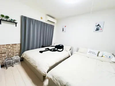 a bedroom with two beds and a black cat sitting on top at \u5927\u585a\u99c55\u52064\u4eba\u53ef in Tokyo