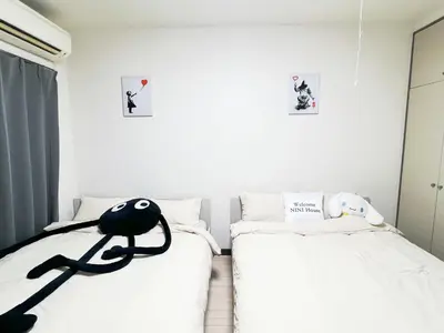 a bedroom with two beds and a black doll on the bed at \u5927\u585a\u99c55\u52064\u4eba\u53ef in Tokyo