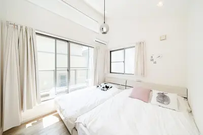 two beds in a bedroom with a large window at 65, Simotakaido A, Entire house for rent, \u4e0b\u9ad8\u4e95\u6238A in Tokyo