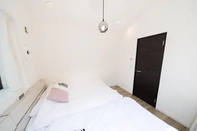 a white bedroom with a bed and a black door at 65, Simotakaido A, Entire house for rent, \u4e0b\u9ad8\u4e95\u6238A in Tokyo