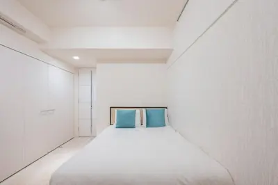 a white room with a bed with two blue pillows at \u30b0\u30e9\u30f3\u30c9\u30b3\u30f3\u30b7\u30a7\u30eb\u30b8\u30e5\u516d\u672c\u6728 in Tokyo