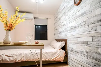 a bedroom with a wooden accent wall and a table at B12\u6c60\u888b\u4e2d\u5fc3 \u4e09\u5ba4 \u4ea4\u901a\u4fbf\u5229 \u8f66\u7ad93\u5206\u949f 3 rooms Ikebukuro center 3 mins to ST Max 8P \u76f4\u8fbe\u65b0\u5bbf \u6d89\u8c37 \u8868\u53c2\u9053 \u6c60\u888b \u4e0a\u91ce \u4ee3\u4ee3\u6728 \u94f6\u5ea7 \u539f\u5bbf in Tokyo