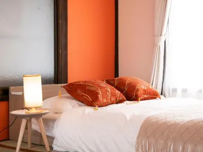 a bed with orange walls and a candle on a table at 6min to subway, Skytree,Ueno,Asakusa within 20min in Tokyo