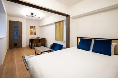 a bedroom with a large bed with blue pillows at \u30d7\u30ec\u30fc\u30eb \u30c9\u30a5\u30fc\u30af\u83ca\u5ddd in Tokyo
