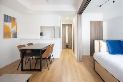 a room with a bed and a table and chairs at \u30d7\u30ec\u30fc\u30eb \u30c9\u30a5\u30fc\u30af\u83ca\u5ddd in Tokyo