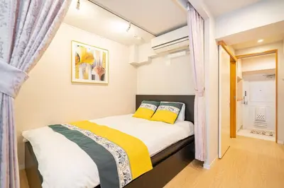 a small bedroom with a bed with yellow pillows at One Bedroom Family Suite Close Ikebukuro Max 4ppl in Tokyo