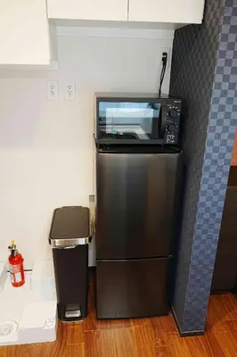 a microwave sitting on top of a refrigerator in a kitchen at 100 INN Standard in Tokyo