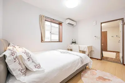a white bedroom with a bed and a mirror at W Hostel in Tokyo