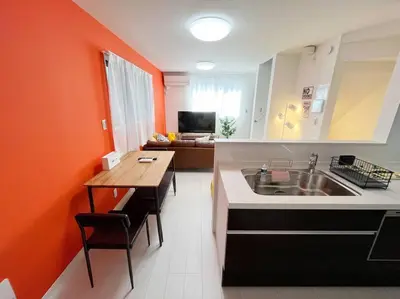 a kitchen with an orange wall and a sink and a table at Good access 3LDK 15 people! Spacious room in Tokyo