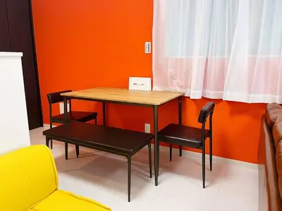 a table and chairs in a room with an orange wall at Good access 3LDK 15 people! Spacious room in Tokyo