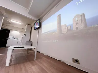 a white table in a room with a large projection screen at Shinjuku 3 min walk from stationp #projector OH33 in Tokyo