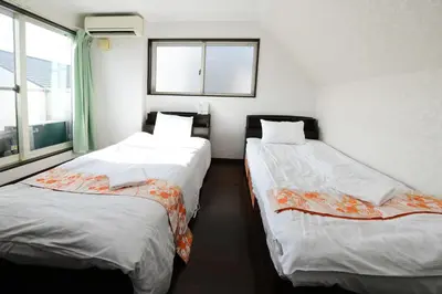 two beds in a room with a window at JING HOUSE\u4eac\u6210\u9ad8\u7802\u99c55\u5206\u8c6a\u83ef\u4e00\u6238\u5efa\u3066\u6700\u59278\u4eba\u6210\u7530\u7fbd\u7530\u76f4\u901a\u7121\u6599\u99d0\u8eca\u6d45\u8349\u30b9\u30ab\u30a4\u30c4\u30ea\u30fc\u8fd1\u304ftokyo narita in Tokyo