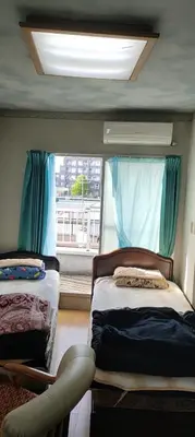a bedroom with two beds and a window with blue curtains at \u30ef\u30f3\u30d5\u30ed\u30a2\u8cb8\u5207 in Tokyo
