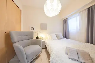 a bedroom with a bed and a chair and a chandelier at Shinjuku Kabukicho Designer's Apartment IV in Tokyo