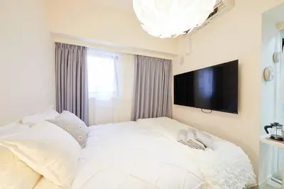 a bedroom with a white bed with a flat screen tv at Shinjuku Kabukicho Designer's Apartment IV in Tokyo