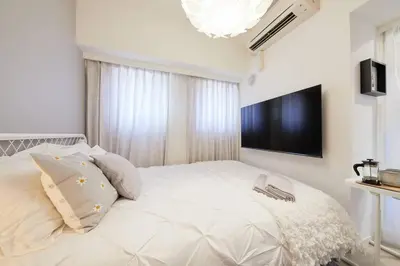 a bedroom with a large white bed with a flat screen tv at Shinjuku Kabukicho Designer's Apartment V in Tokyo