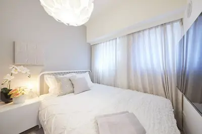 a white bedroom with a white bed and a chandelier at Shinjuku Kabukicho Designer's Apartment V in Tokyo