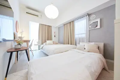 a white bedroom with two beds and a table at Shinjuku Kabukicho Designer's Apartment VI in Tokyo