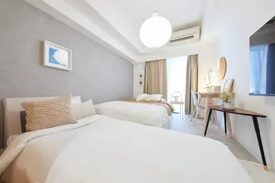 a white bedroom with two beds and a table at Shinjuku Kabukicho Designer's Apartment VII in Tokyo