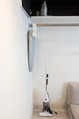 a room with a white wall with a floor vacuum at Skyfeel Okubo A in Tokyo