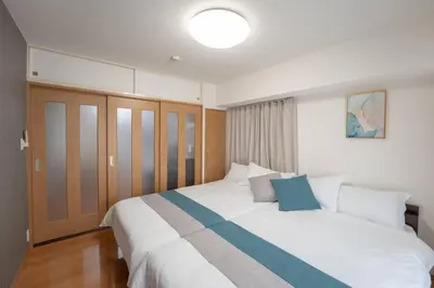 a bedroom with a large white bed with blue accents at 12 MIN walk to Shinjuku STR ,6 MIN Higashishinjuku ,nearest kabukicho ,shinjuku oen, in Tokyo