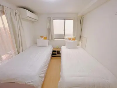two beds in a room with a window at JINGHOUSE Takasago detached house - Vacation STAY 17050 in Tokyo