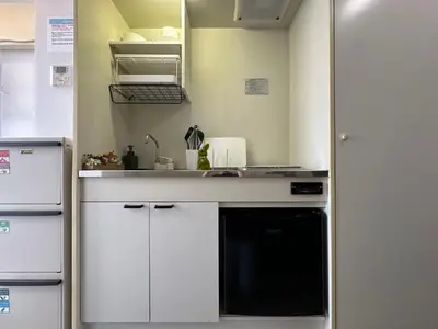 a kitchen with white cabinets and a black dishwasher at nestay inn tokyo waseda in Tokyo
