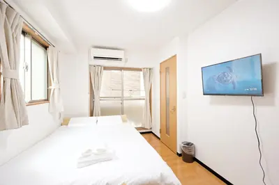 a bedroom with a bed and a tv on a wall at Mi-APT MIDORI in Tokyo